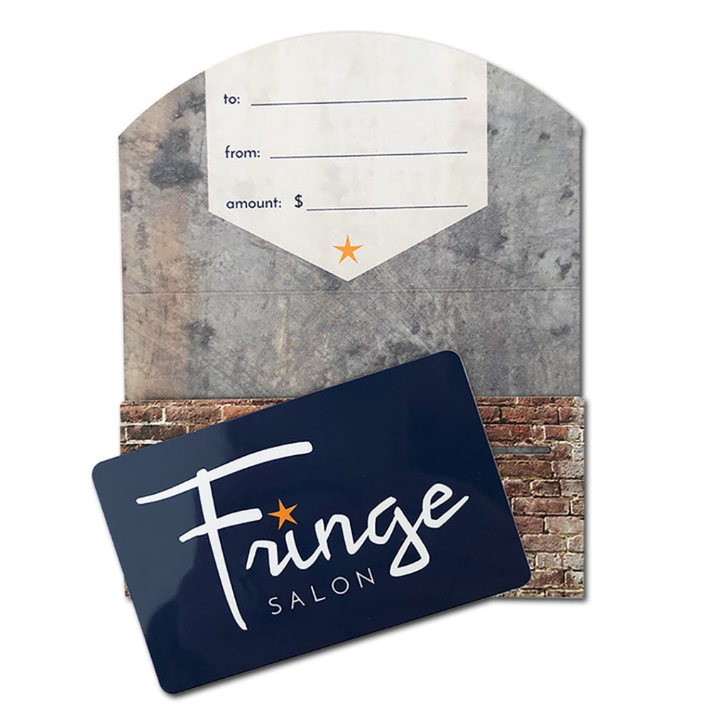 Fringe Salon Gift Card | Gift card is navy blue plastic with white logo. Gift card enclosure has semi-circular flap printed with brick and aged metal patterns. Flap has fields to write to, from, and gift amount.