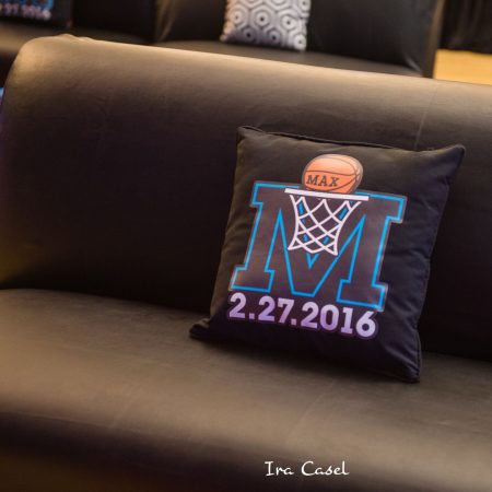 Black pillow with basketball bar mitzvah logo on black couch.