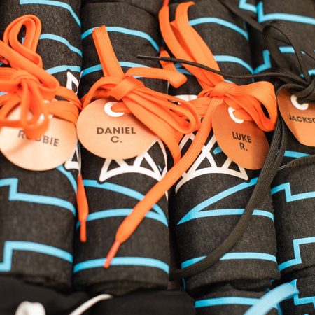 Black tee shirts with basketball logo, rolled up and secured with shoe laces and name tags.